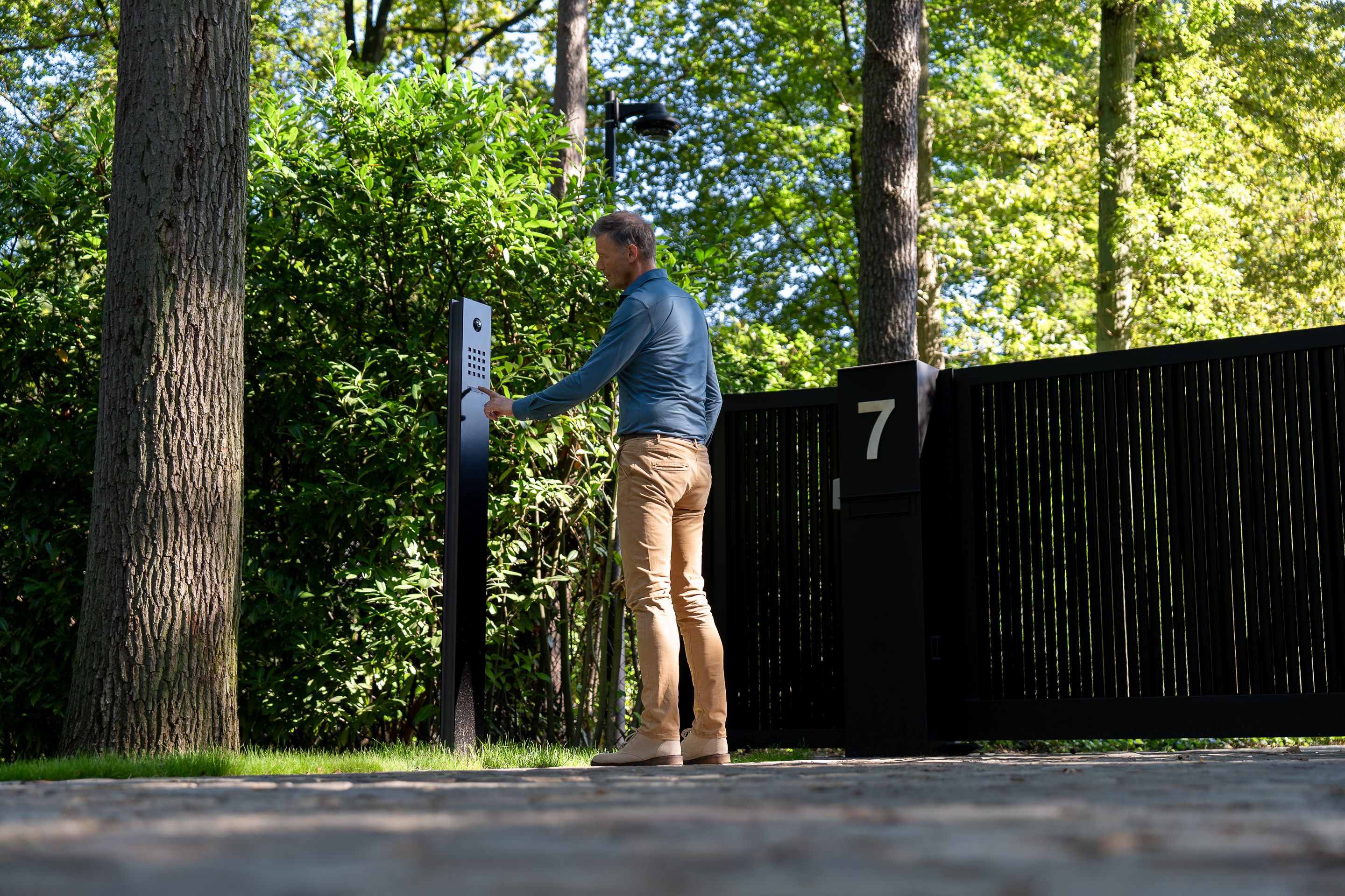 Een man gebruikt het geïntegreerd toegangssysteem voor de poort van zijn woning om binnen te gaan.